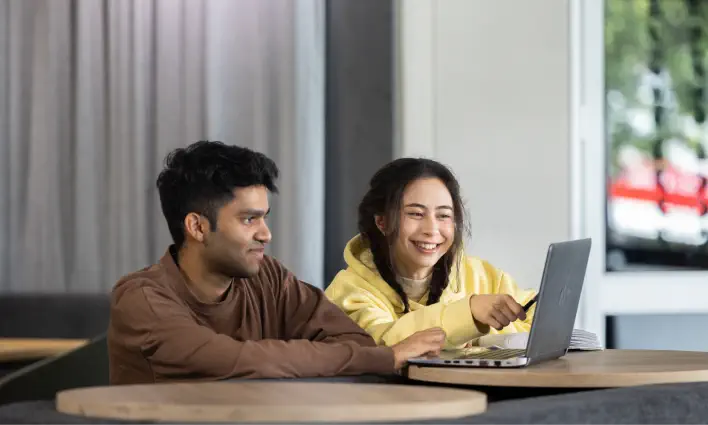 two-students-smiling-at-laptop-screen